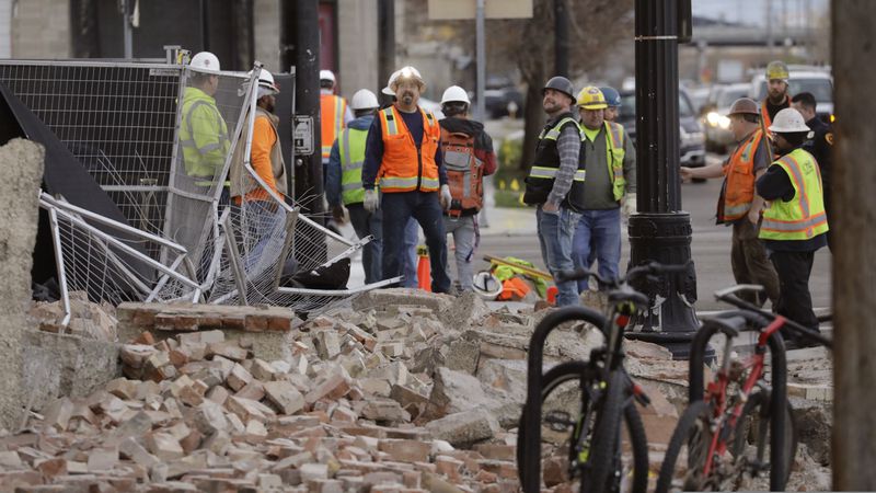 Construction workers looks at the rubble from a building after an earthquake Wednesday, March 18, 2020, in Salt Lake City.  A 5.7-magnitude earthquake has shaken the city and many of its suburbs. The quake sent panicked residents running to the streets, knocked out power to tens of thousands of homes and closed the city's airport and its light rail system.  (AP Photo/Rick Bowmer)