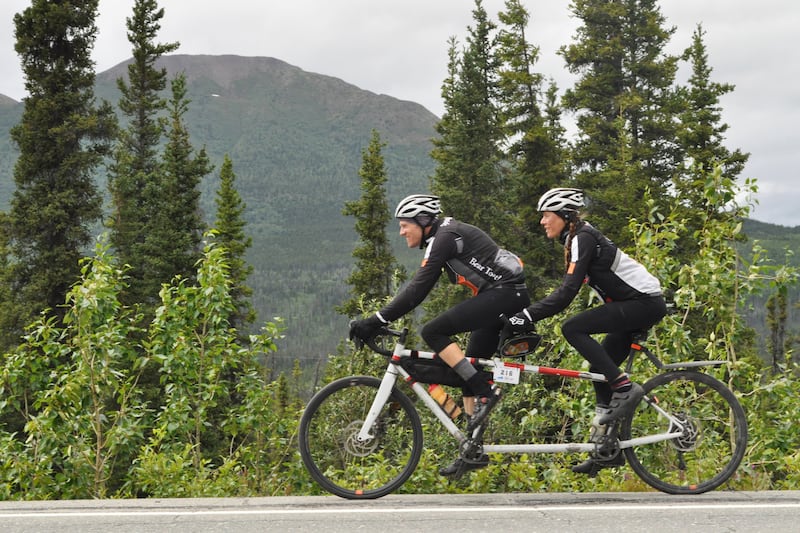 Andy Pohl and Kristy Berington — a longtime musher who's completed the Iditarod Trail Sled Dog Race 13 times — ride a tandem bicycle along the Richardson Highway south of Tonsina en route to Valdez in the 200-mile Fireweed bike race on Saturday, July 13, 2024. (Vicky Ho / ADN)