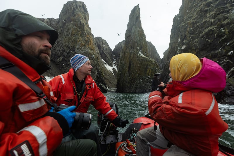 Deckhand Patrick Farnell operates a skiff near the columnar basalt formations on St. Matthew Island to give scientists a closer look at the birds nesting there. (Photo by Nathaniel Wilder)