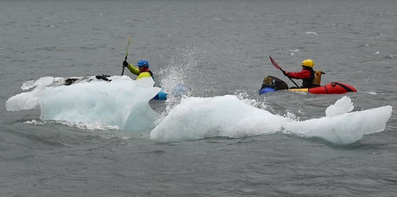 During a windy and rainy day, Brittni Driver of Fairbanks and Hector Plaza of New York City, who met while working in Antarctica, paddle pack rafts past waves crashing against Portage Glacier icebergs grounded near the Begich, Boggs Visitor Center at Portage Lake, on their way to float Portage Creek in the Chugach National Forest on Tuesday, July 16, 2024. Driver said, "I'm showing him the authentic Alaska." (Bill Roth / ADN)