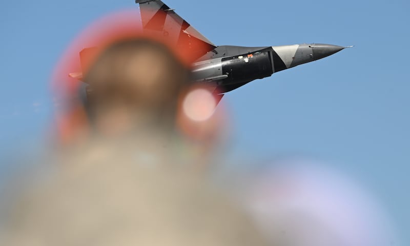 A fighter jet makes a low pass as a spectator with ear protection watches during the Arctic Thunder air show. (Bob Hallinen Photo)
