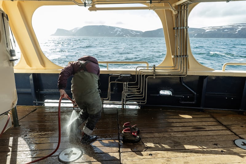 A biologist washes gear after returning to the ship from a transect. Cleaning gear after every visit on island ensures that nothing from one island inadvertently gets transferred to another island in the refuge system. (Photo by Nathaniel Wilder)