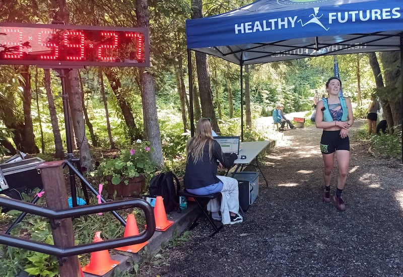 A relieved Jenna DiFolco of Fairbanks crosses the finish line at the Eagle River Nature Center to win first place in the women’s division of the 39th annual Crow Pass Crossing trail race on Saturday, July 20, 2024 in Eagle River. (Josh Reed / ADN )