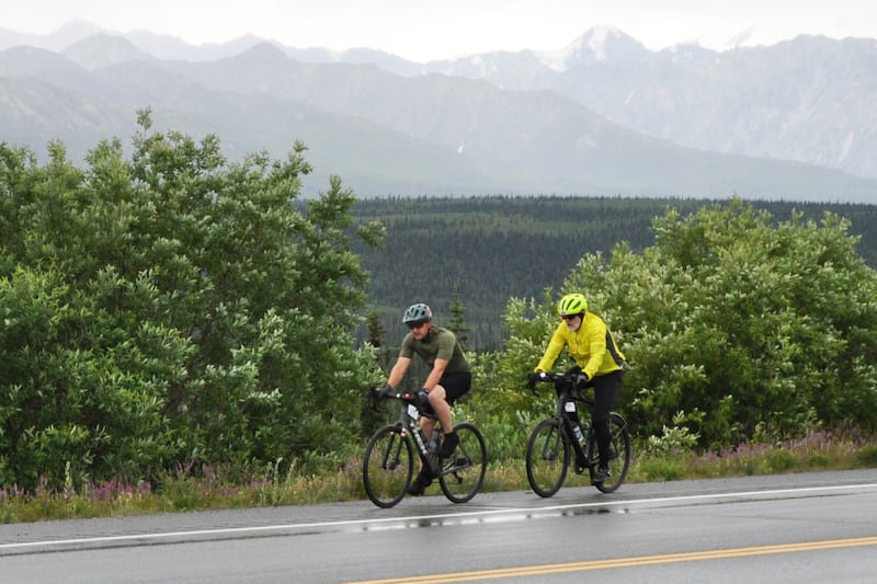 Two cyclists competing in the Fireweed bike race's duos division ride along the Glenn Highway near Eureka Lodge on Saturday, July 13, 2024. (Vicky Ho / ADN)