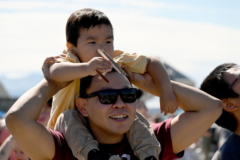 Fred Ulroan holds his son Rylan Ulroan as Rylan holds a homemade airplane during the Arctic Thunder Open House at JBER on Saturday. The father and son, from Chevak, AK, were watching the F-16 demonstration. (Bob Hallinen Photo)

