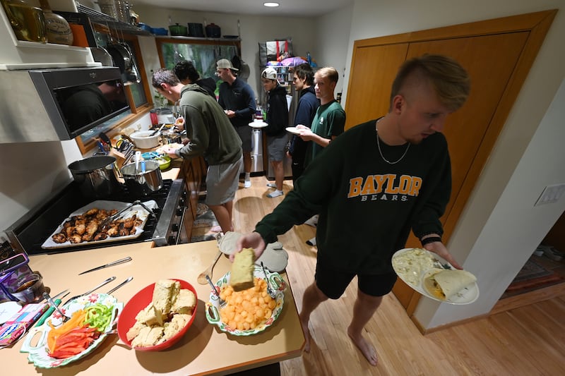 Anchorage Bucs fill their plates in the kitchen of host Jennifer Mattingly during a dinner she provided at her home. (Bill Roth / ADN) 