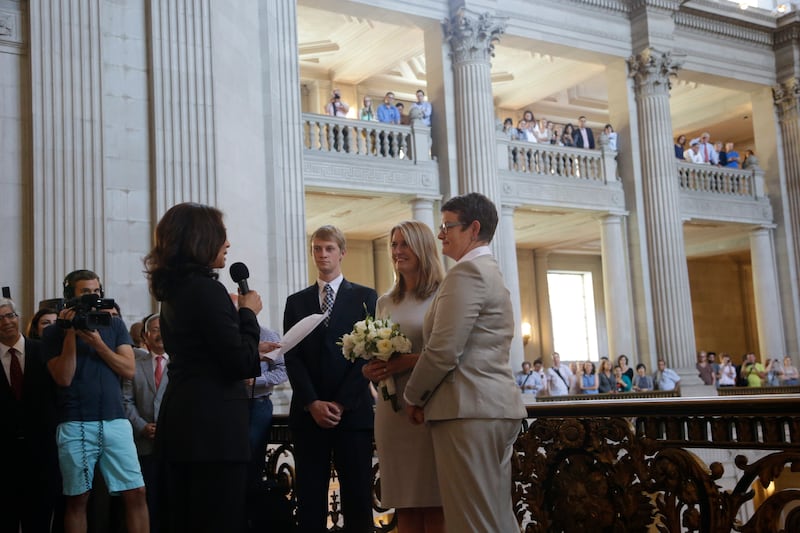 In this June 28, 2013, file photo Sandy Stier, center left, and Kris Perry, at right, exchange wedding vows in front of California Attorney General Kamala Harris, left, at City Hall in San Francisco.  (AP Photo/Marcio Jose Sanchez, File)
