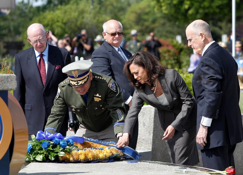 California Highway Patrol Commissioner Joe Farrow, second from left, and Attorney General Kamala Harris, place a wreath honoring those CHP officers killed in the line of duty on the CHP Memorial  as Gov. Jerry Brown, right, looks on during ceremonies at the CHP academy in West Sacramento, Calif., Tuesday, May 7, 2013.  The name of CHP Officer Kenyon Youngstrom, who was shot and killed in Sept. of  2012, was added to the memorial.  Also seen are former CHP Commissioners Glen Craig, left, and Spike Helmick, background third from left.(AP Photo/Rich Pedroncelli) 