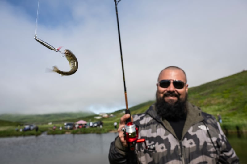 Michael Bendixen hauls in a contender for the smallest fish award during the Independence Day fishing derby in Ram’s Creek in King Cove on July 4, 2024. (Marc Lester / ADN)