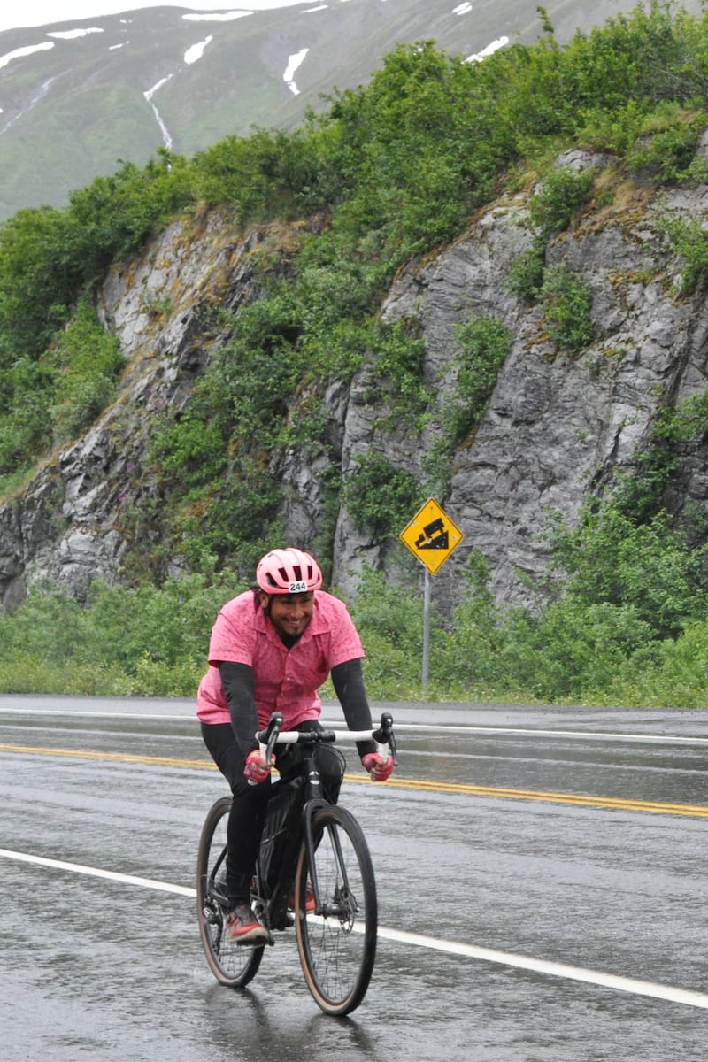 Kevin Enriquez, part of the "Off The Chain" duo, smiles in the rain while riding along the Richardson Highway toward Thompson Pass on Saturday, July 13, 2024, during the 200-mile Fireweed bike race to Valdez. (Vicky Ho / ADN)