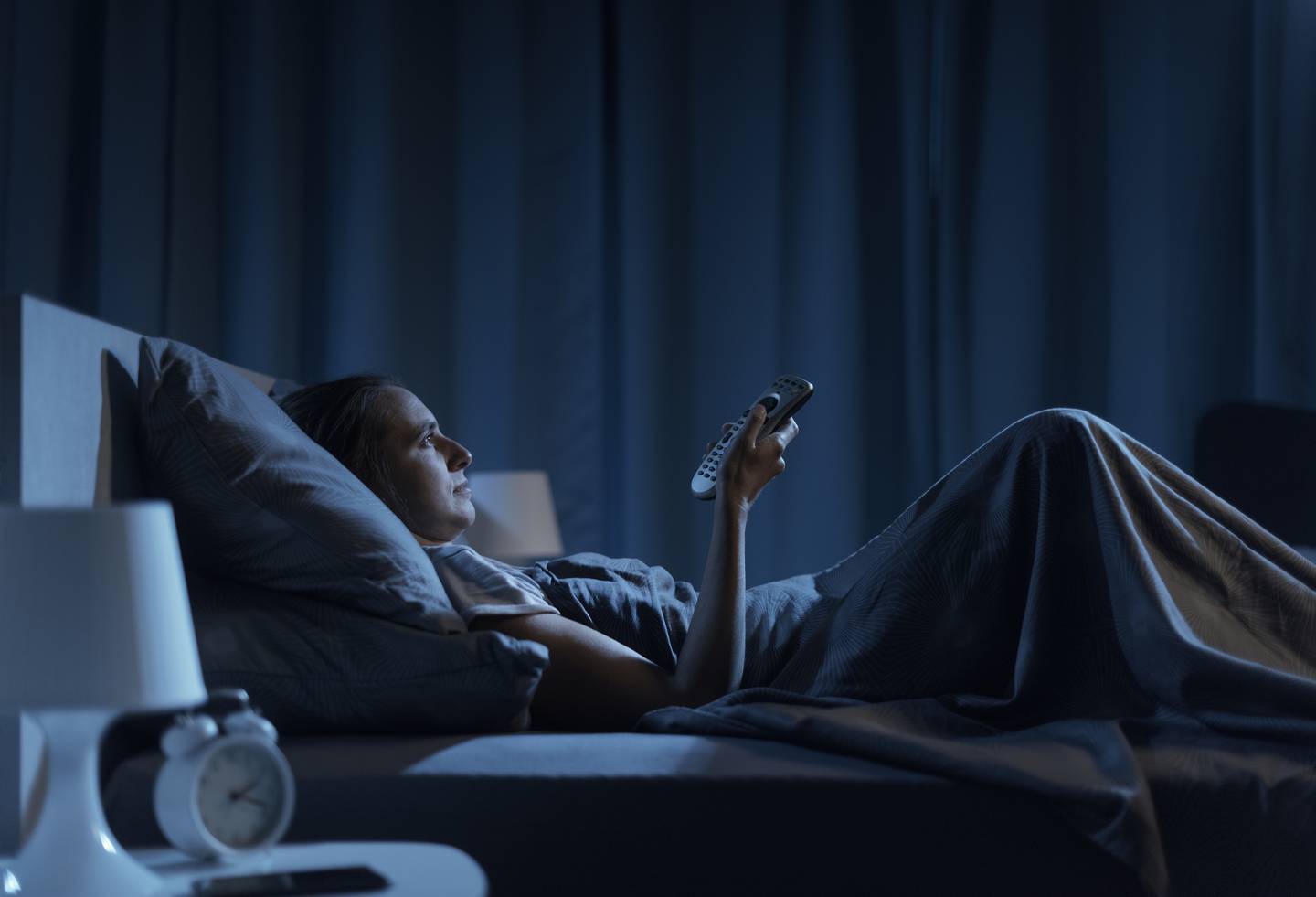 woman watching tv in bed stock